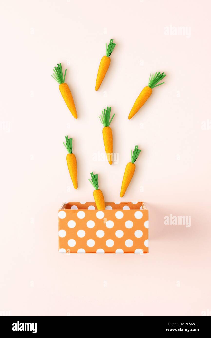 Boîte cadeau avec carottes de Pâques sur fond lumineux. Concept de vacances de printemps minimal. Banque D'Images