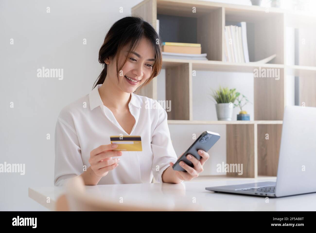 Services bancaires mobiles. Femme utilisant des services bancaires en ligne avec une carte de crédit sur un téléphone mobile. Paiements numériques et Internet achats sur le réseau. Banque D'Images