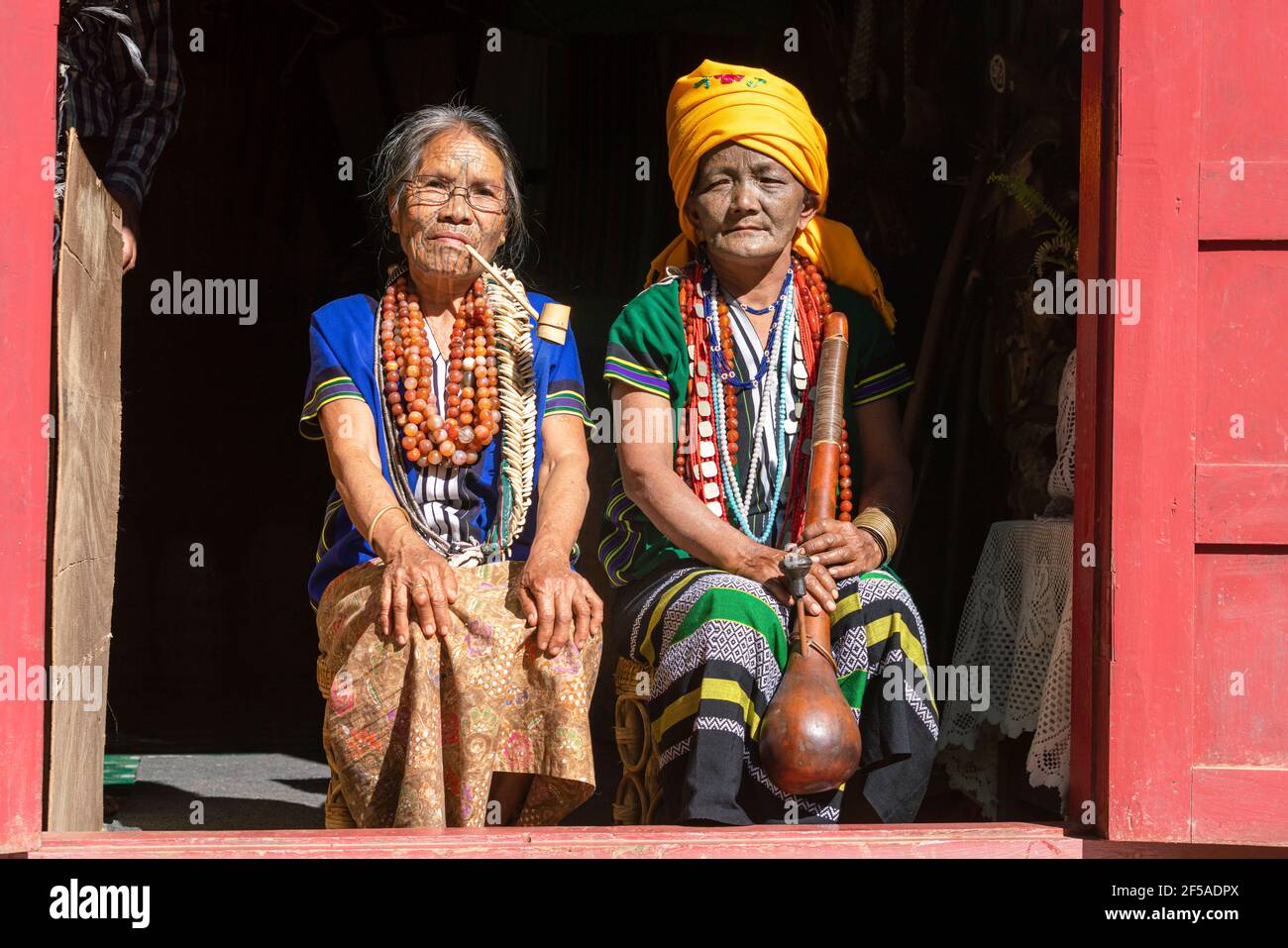 Femmes avec des visages tatoués traditionnels assis au porche, Mindat, Myanmar Banque D'Images