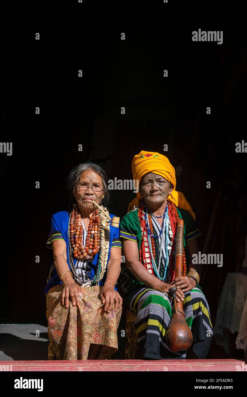 omen avec visages tatoués assis au porche, Mindat, État de Chin, Myanmar Banque D'Images