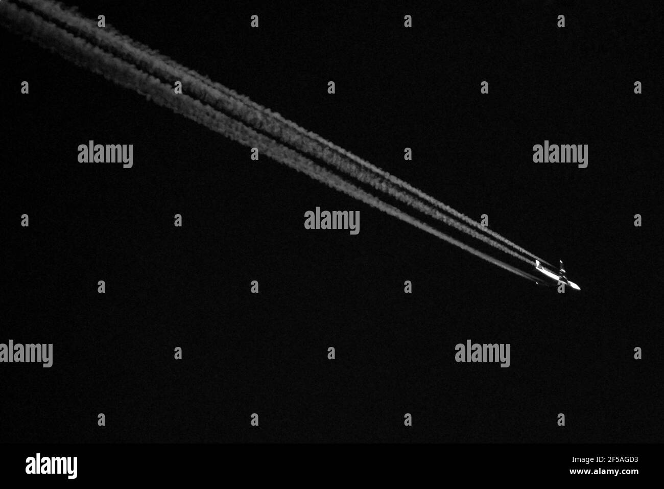 Contrailles d'un avion passant au-dessus de la tête dans le ciel Au-dessus de Surrey dans cette photo en noir et blanc Banque D'Images
