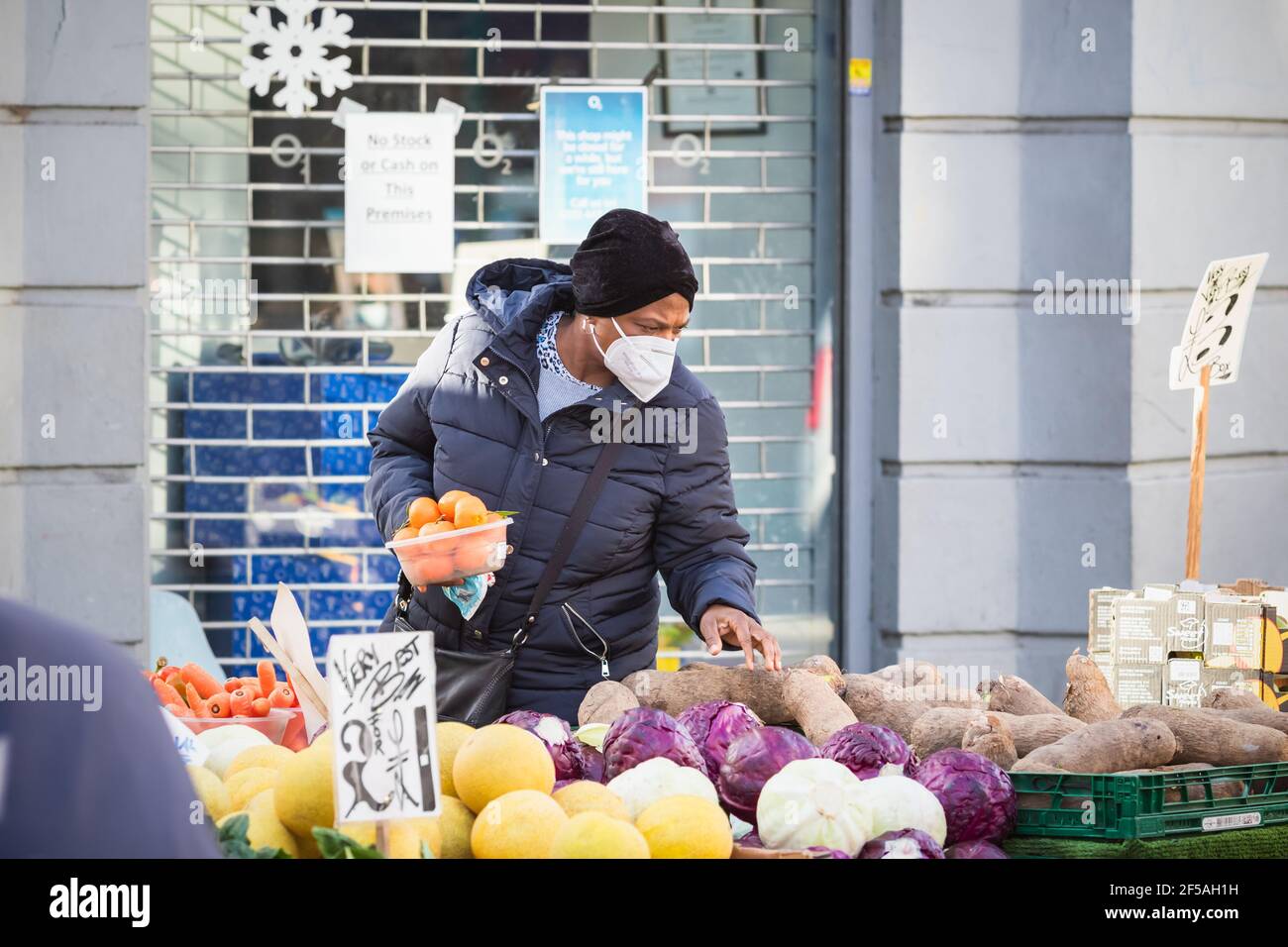 Londres, Royaume-Uni - 5 février 2021 - UNE femme noire portant un masque de protection tout en faisant du shopping dans un stand extérieur de produits de la haute rue de Wood Green Banque D'Images