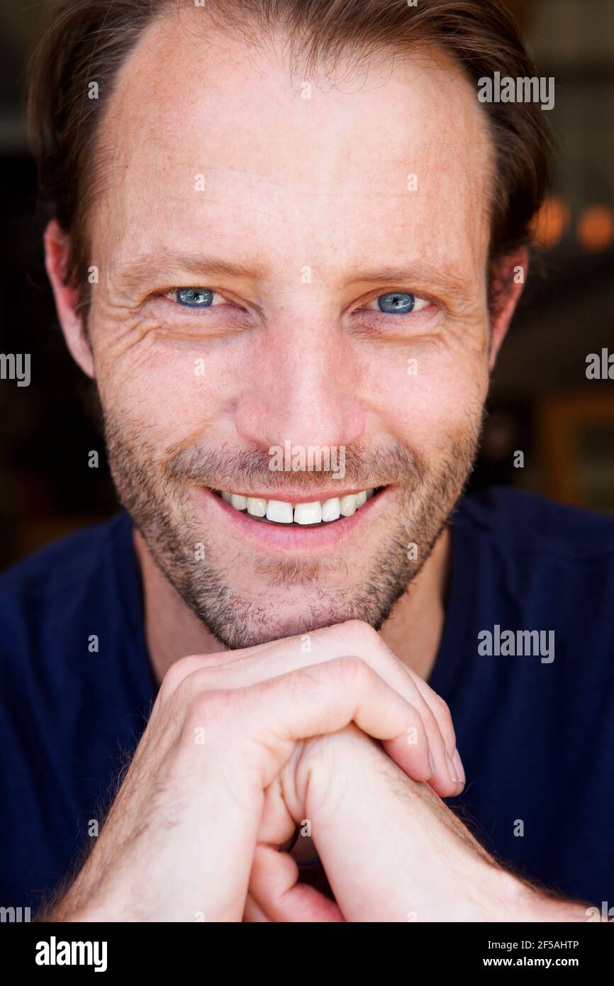 Gros plan d'un beau homme plus âgé souriant à la main jusqu'au menton Banque D'Images