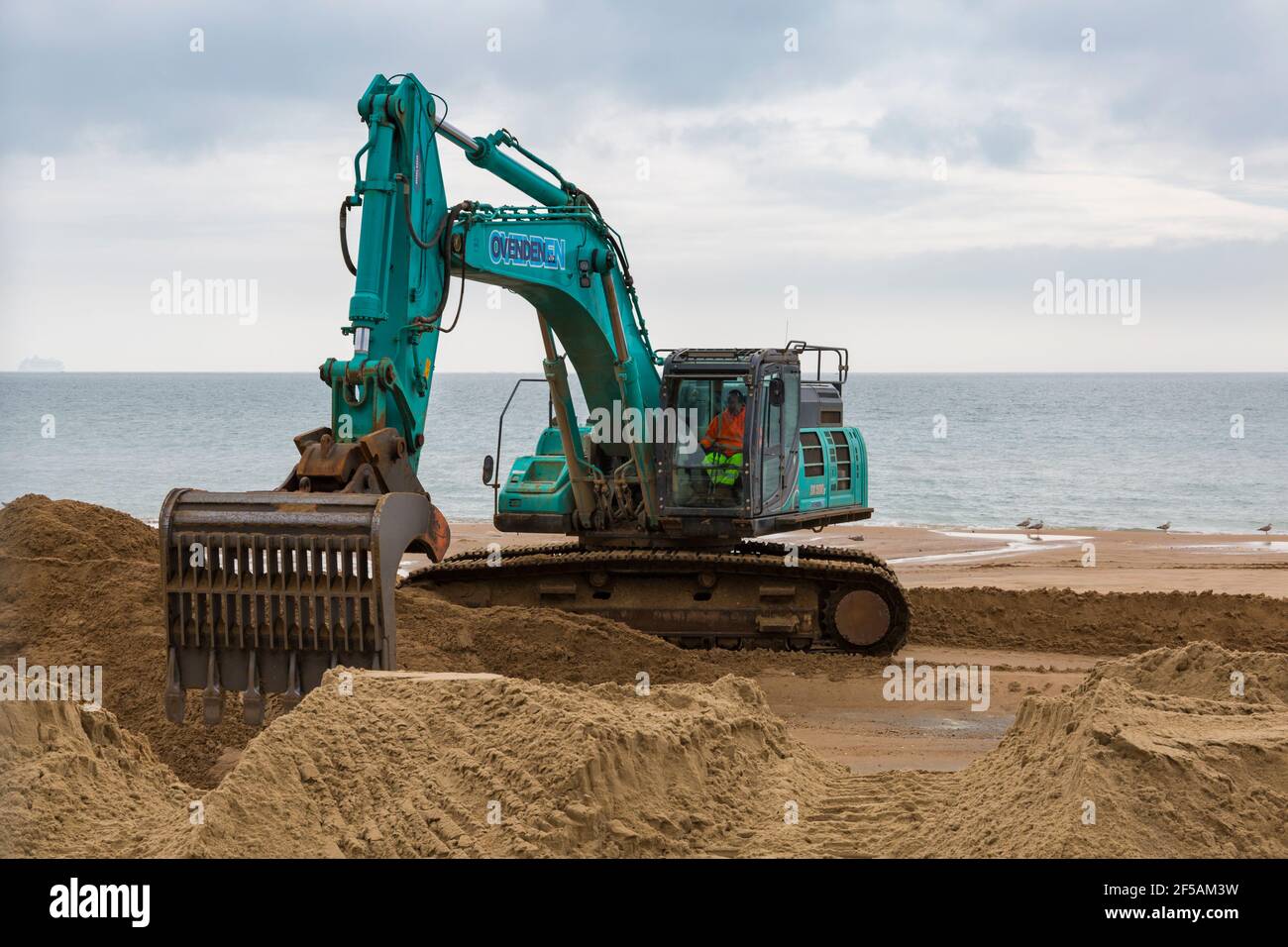 Pelle excavatrice Ovenden SK500 excavateur déplacement du sable sur la plage pour des travaux de réapprovisionnement de plage à Bournemouth et Poole Beaches, Dorset UK en mars Banque D'Images