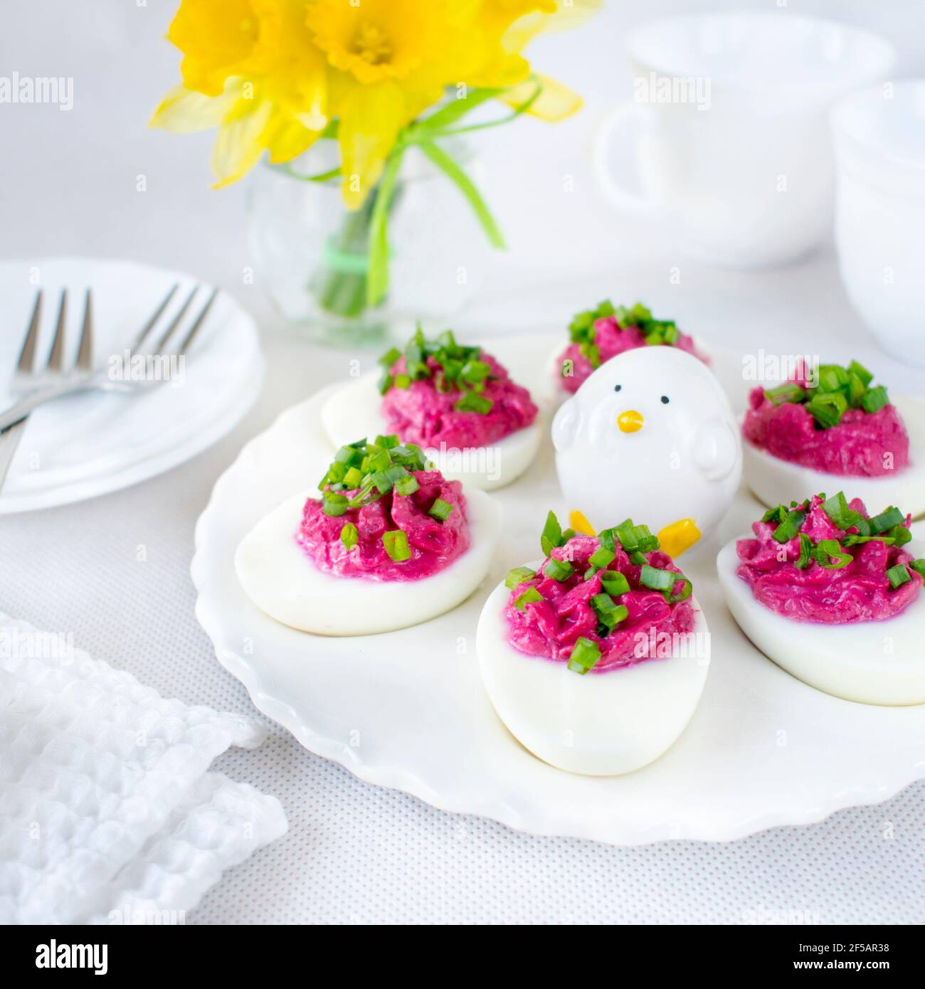 Œufs durs farcis avec de la pâte de betteraves et saupoudrés de ciboulette. Banque D'Images