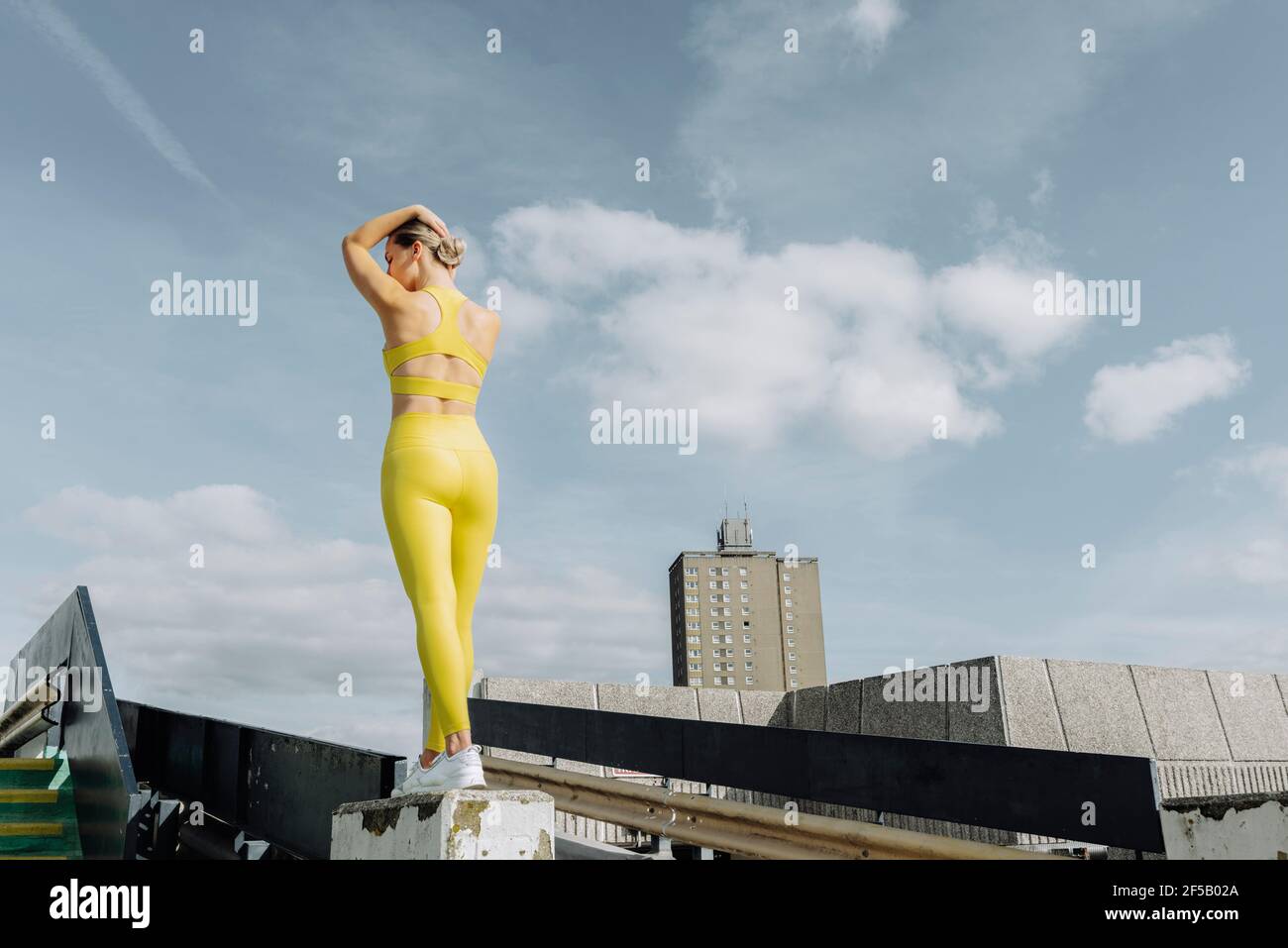 femme sportive attrayante portant des vêtements d'activité jaunes debout à l'extérieur, sur le toit. Banque D'Images femme sportive attrayante portant des vêtements d'activité jaunes debout à l'extérieur, sur le toit. Banque D'Images