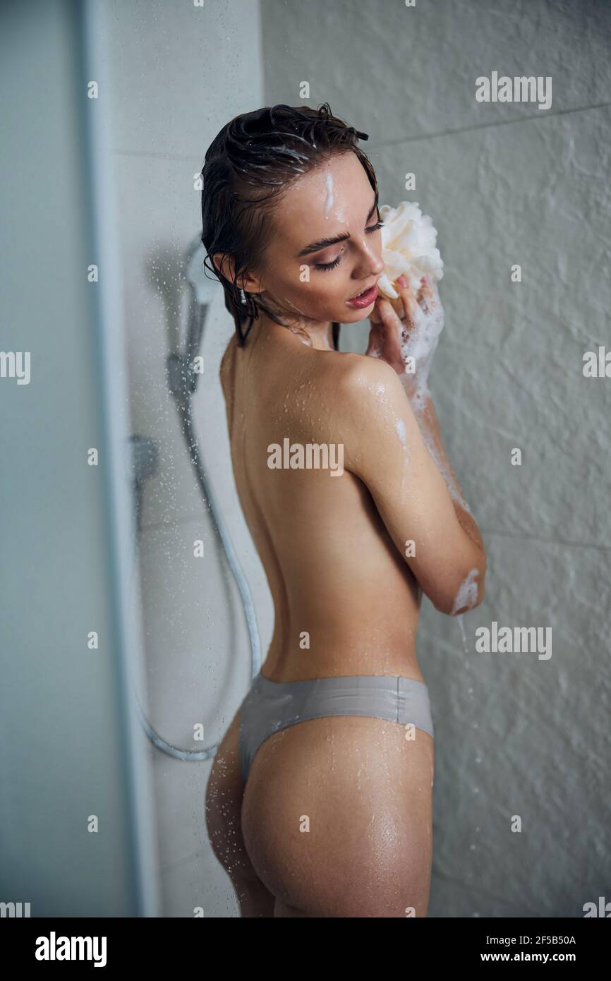 Femme lavant son corps avec une éponge de bain Banque D'Images