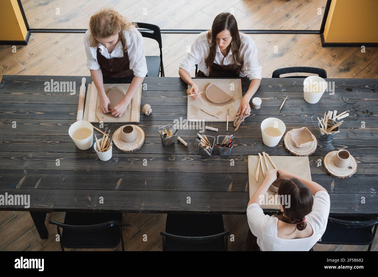 Femmes travaillant dans un studio de poterie, souriant et parlant. Atelier de céramique, cours de maître en poterie Banque D'Images