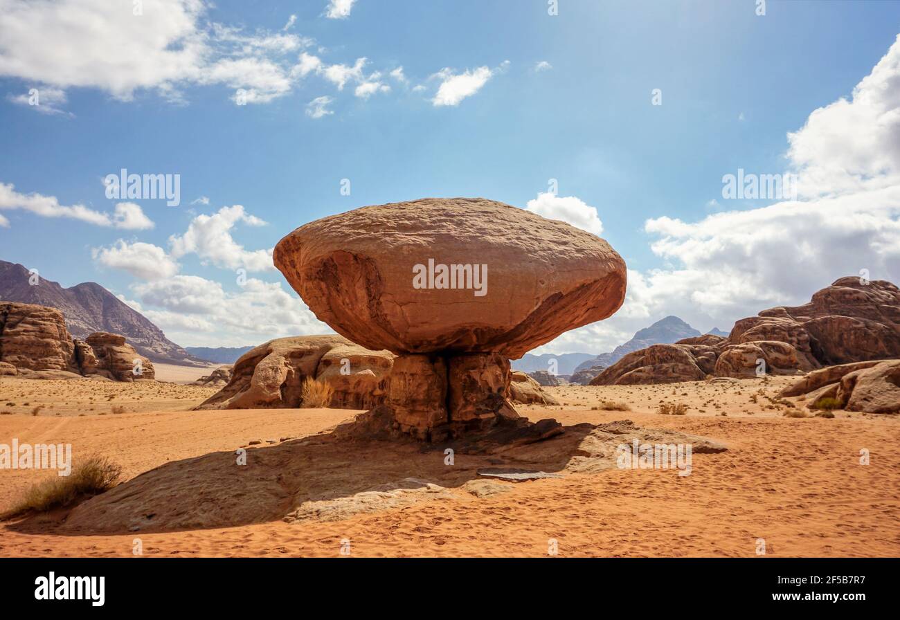 Rocher en forme de champignon dans le désert de Wadi Rum, soleil éclatant brille sur fond de montagnes Banque D'Images