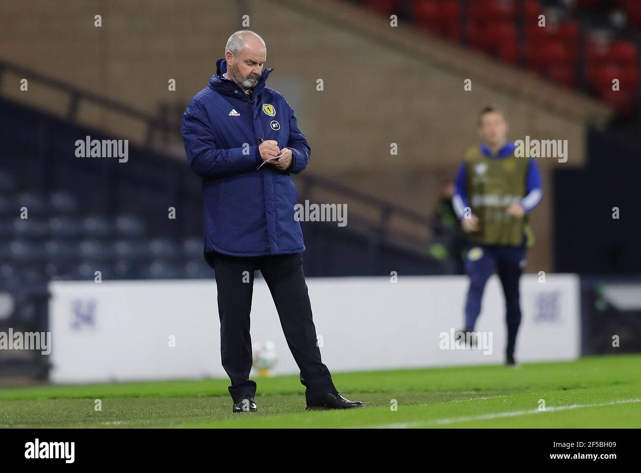 Steve Clarke, entraîneur-chef écossais, écrit dans un carnet de notes sur la ligne de contact lors du match de qualification de la coupe du monde de la FIFA 2022 à Hampden Park, Glasgow. Date de la photo: Jeudi 25 mars 2021. Banque D'Images