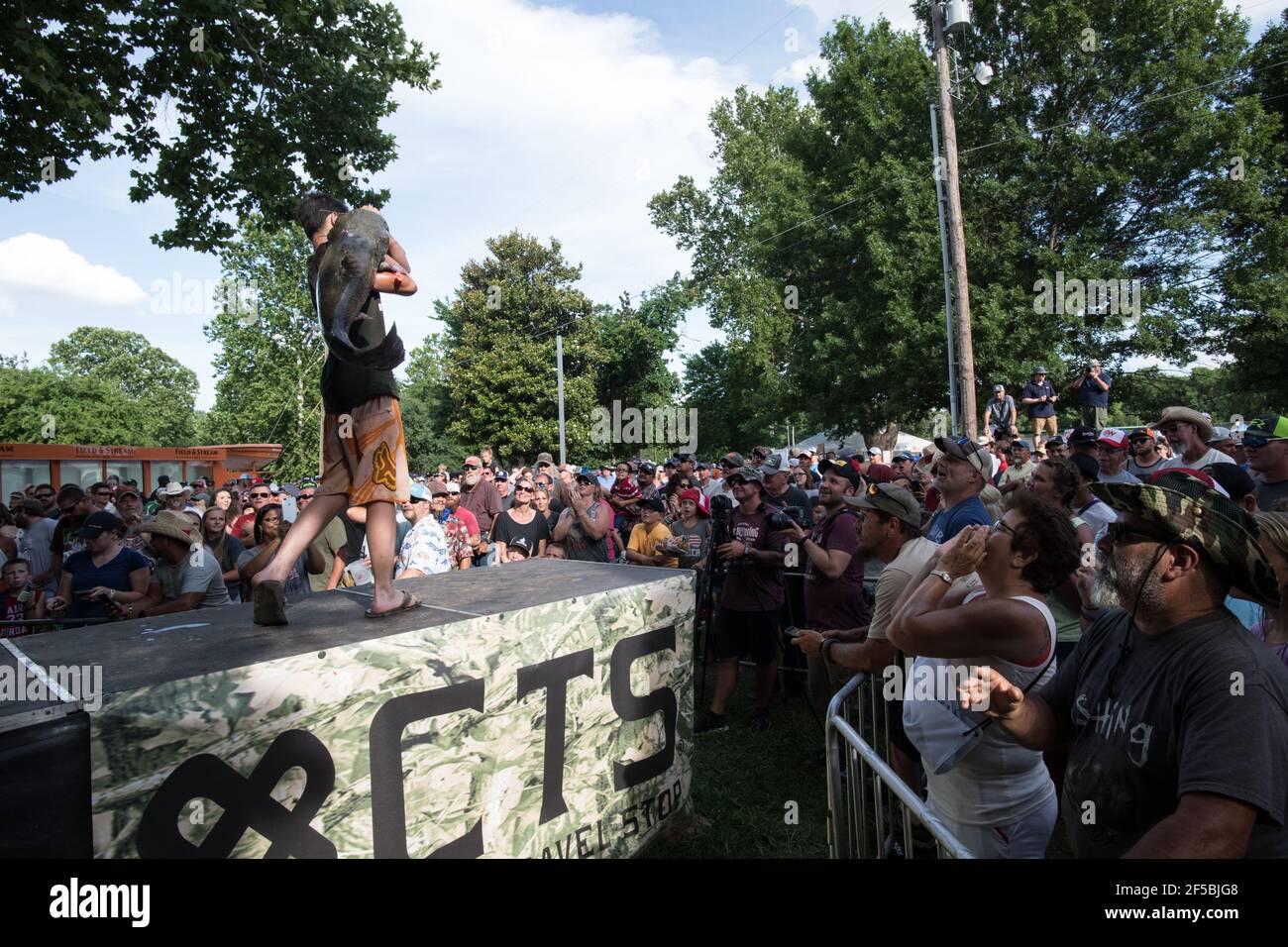 Un nouiller triomphant expose fièrement son poisson-chat à une foule enthousiaste lors du tournoi annuel Okie Noodling à Paul's Valley, Oklahoma. Banque D'Images
