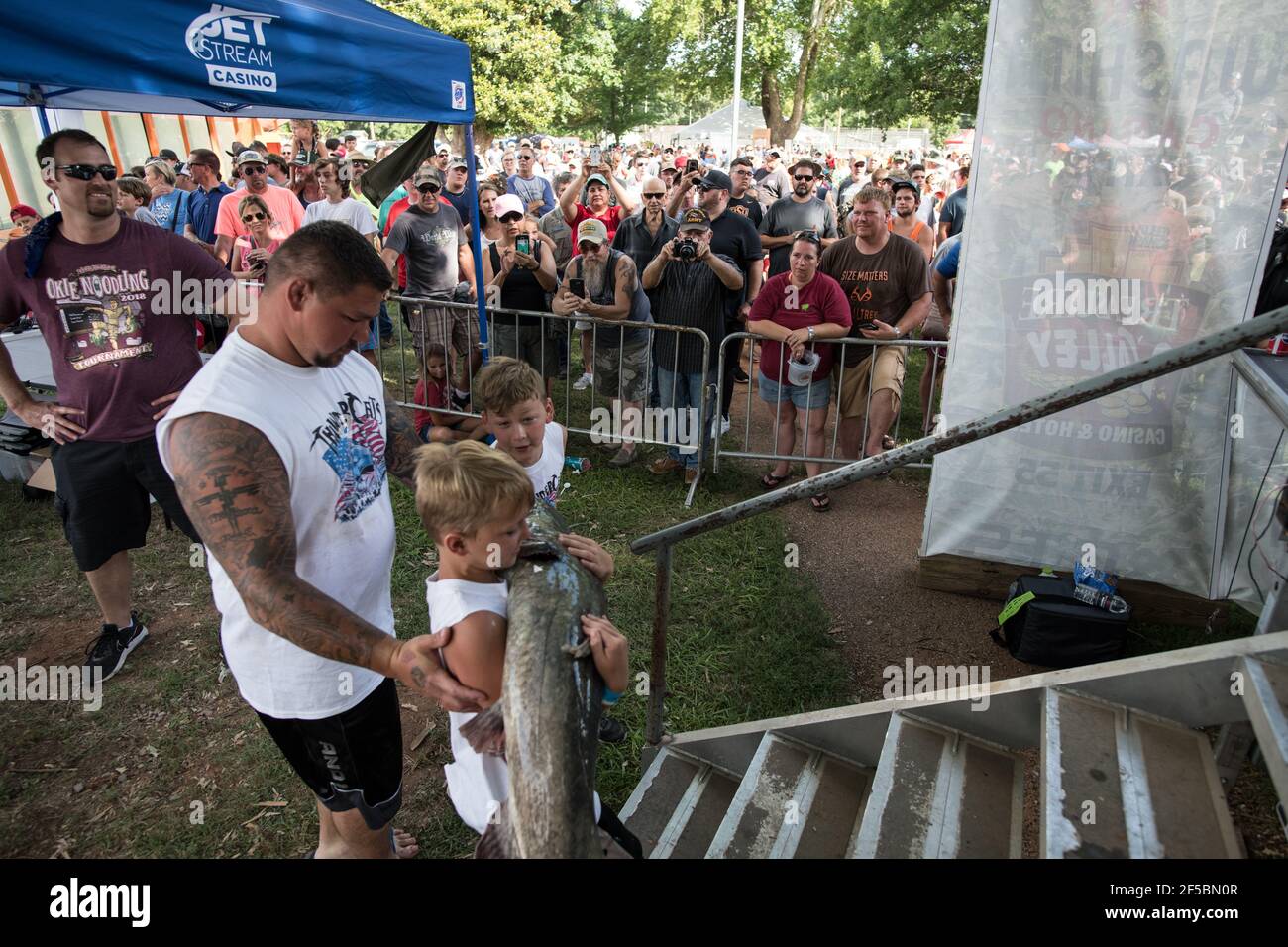 Un nouiller triomphant expose fièrement son poisson-chat à une foule enthousiaste lors du tournoi annuel Okie Noodling à Paul's Valley, Oklahoma. Banque D'Images
