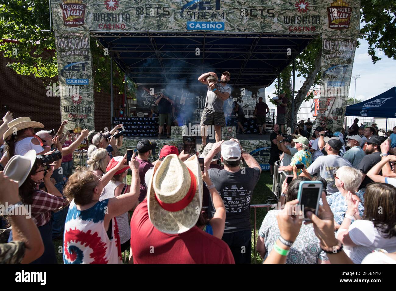 Un nouiller triomphant expose fièrement son poisson-chat à une foule enthousiaste lors du tournoi annuel Okie Noodling à Paul's Valley, Oklahoma. Banque D'Images