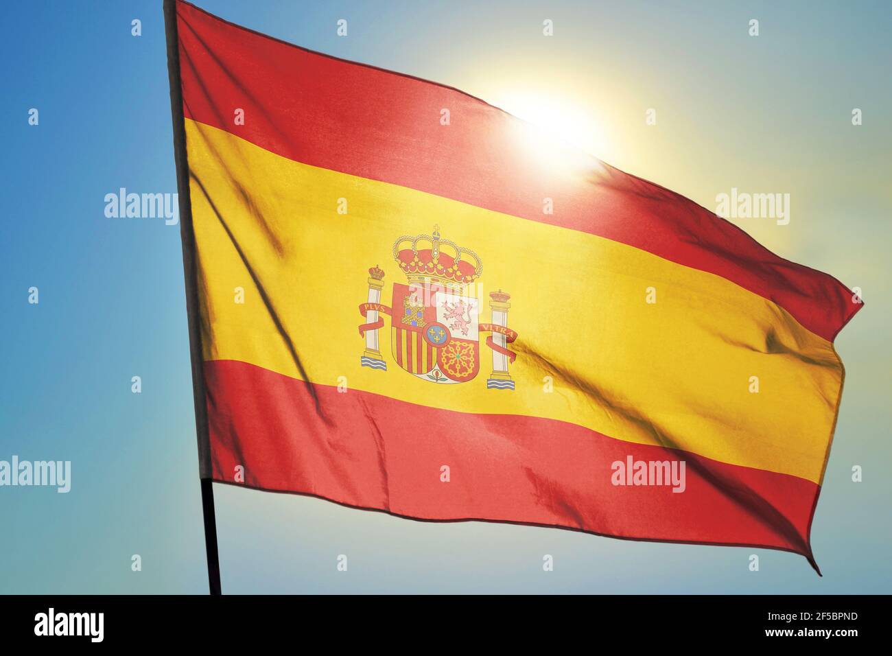 Drapeau espagnol agitant sur le vent devant le soleil Banque D'Images