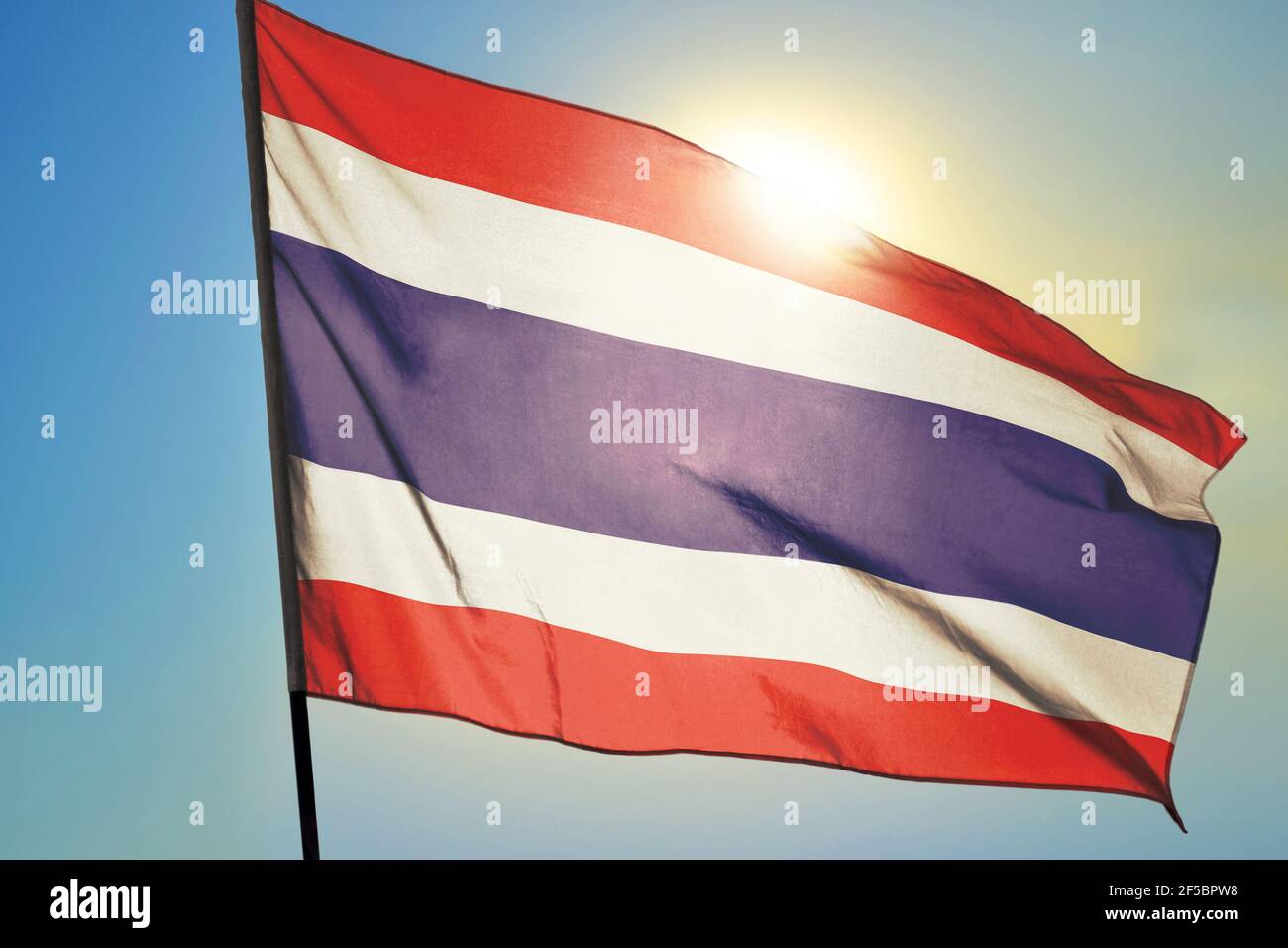 Drapeau thaïlandais agitant sur le vent devant le soleil Banque D'Images