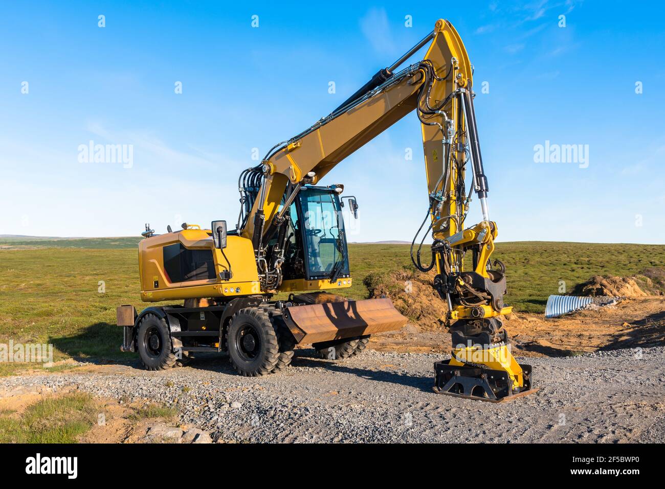 Pelle hydraulique sur roues sur un site de construction routière à la campagne au coucher du soleil Banque D'Images