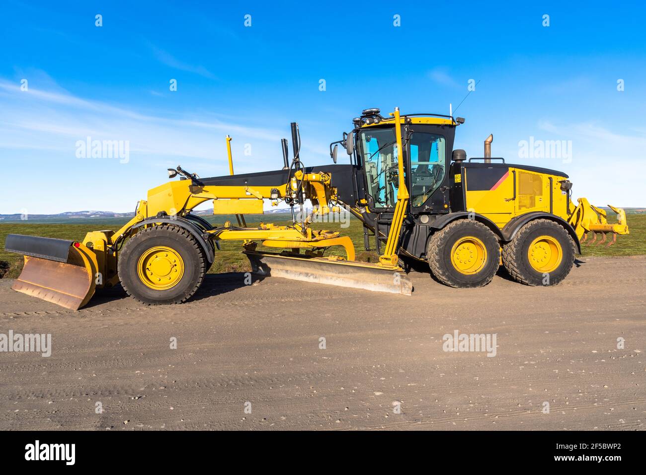 Niveleuse dans un chantier de construction de routes sous ciel bleu Banque D'Images