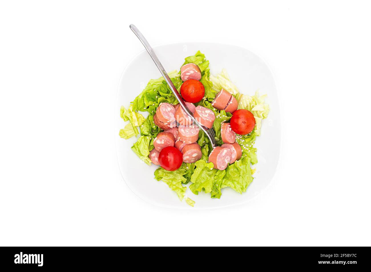 Salade fraîche mélangée avec wurstel dans un bol. Salade brute sur fond blanc. Vue de dessus Banque D'Images