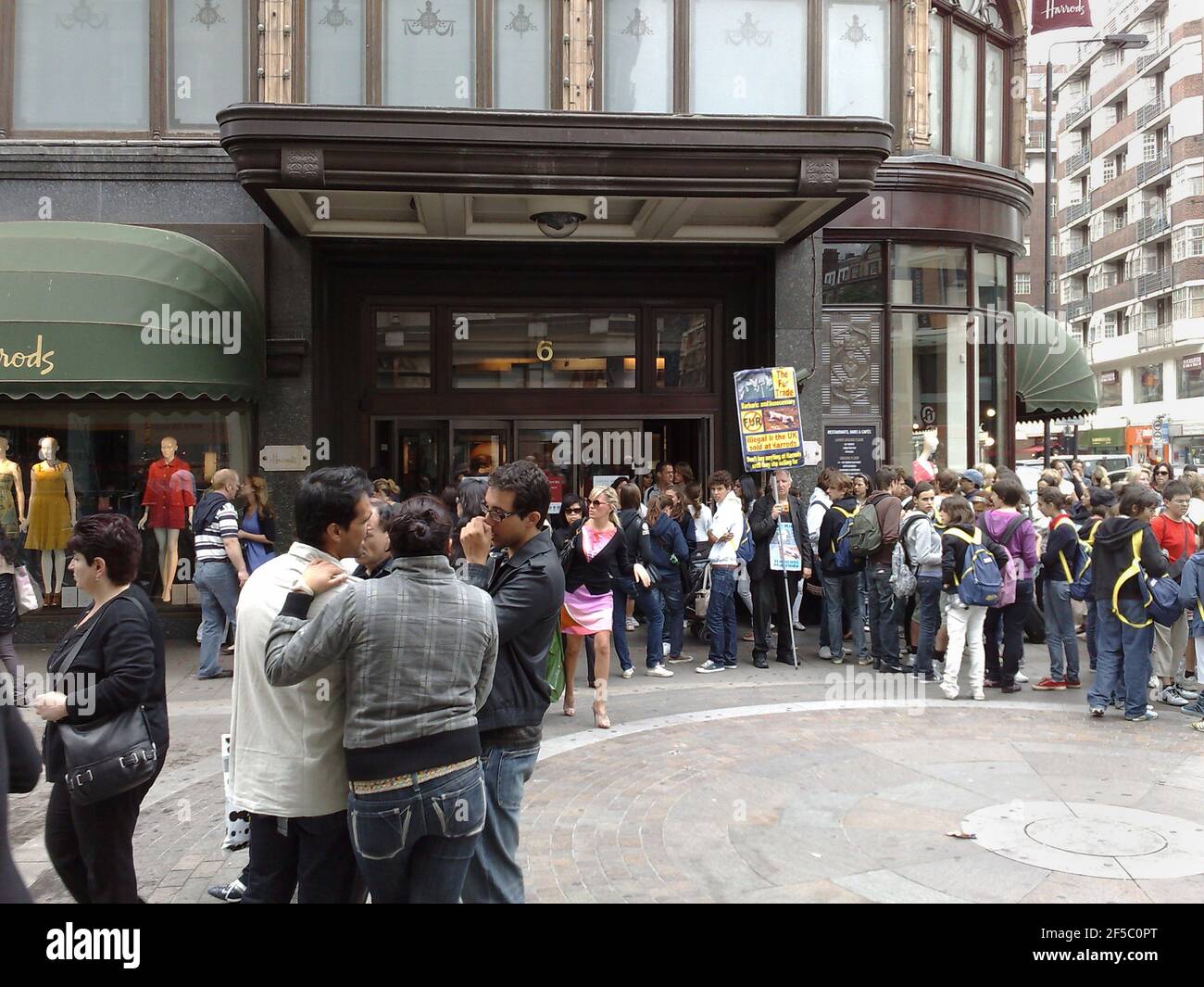 Scène de rue à l'extérieur de Harrod's à Londres, avec beaucoup de gens et un manifestant contre la fourrure avec bannière Banque D'Images