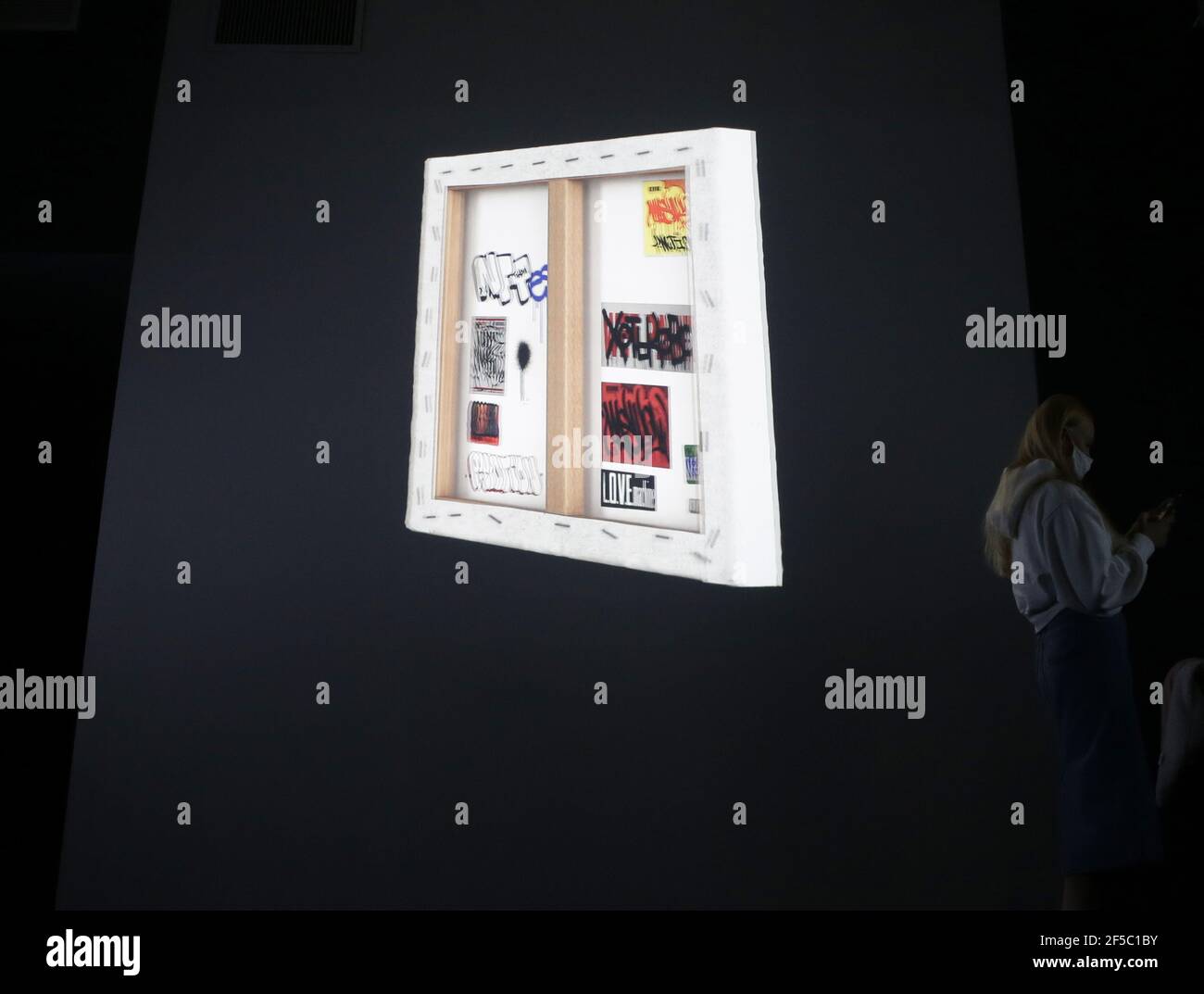 New York, États-Unis. 25 mars 2021. Les gens passent par les œuvres d'art de la NFT et les regardent lors d'un aperçu de presse et de l'ouverture officielle de la galerie SuperChief NFT, la galerie physique du monde consacrée exclusivement aux œuvres d'art de la NFT (jetons non fongibles) à New York le jeudi 25 mars 2021. La galerie s'ouvre avec l'exposition « Season One Starter Pack », qui présente une rotation quotidienne des installations artistiques affichées sur des écrans 4K haute résolution. Photo de John Angelillo/UPI crédit: UPI/Alay Live News Banque D'Images