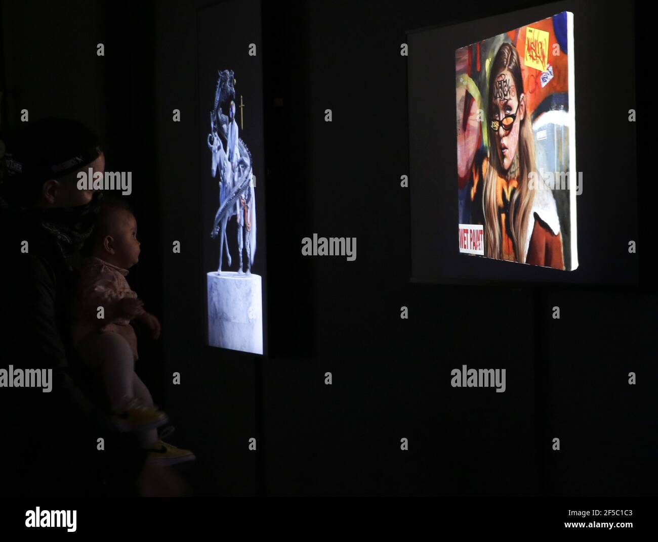 New York, États-Unis. 25 mars 2021. Les gens passent par les œuvres d'art de la NFT et les regardent lors d'un aperçu de presse et de l'ouverture officielle de la galerie SuperChief NFT, la galerie physique du monde consacrée exclusivement aux œuvres d'art de la NFT (jetons non fongibles) à New York le jeudi 25 mars 2021. La galerie s'ouvre avec l'exposition « Season One Starter Pack », qui présente une rotation quotidienne des installations artistiques affichées sur des écrans 4K haute résolution. Photo de John Angelillo/UPI crédit: UPI/Alay Live News Banque D'Images