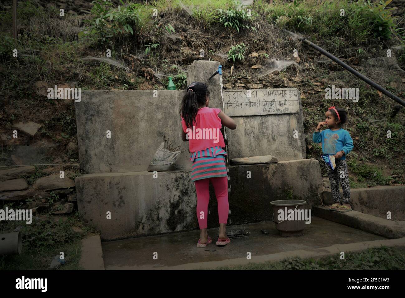 Un enfant et sa petite sœur prennent de l'eau dans une installation commune d'eau dans le village de Damdame, dans la région de Panchase, dans l'État de Gandaki Pradesh, au Népal. En 2017, environ 4.2 milliards de personnes, soit 55 % de la population mondiale, n'avaient pas accès à des services d'assainissement gérés en toute sécurité, selon ONU Water dans leur Résumé Progress Update 2021, publié le 1er mars 2021 à Genève. Pendant ce temps, plus de 3 milliards de personnes dans le monde sont actuellement en danger en utilisant l'eau parce que la santé de leur source d'eau (rivières, lacs ou eaux souterraines) est inconnue en raison du manque de données sur la qualité de l'eau. Banque D'Images