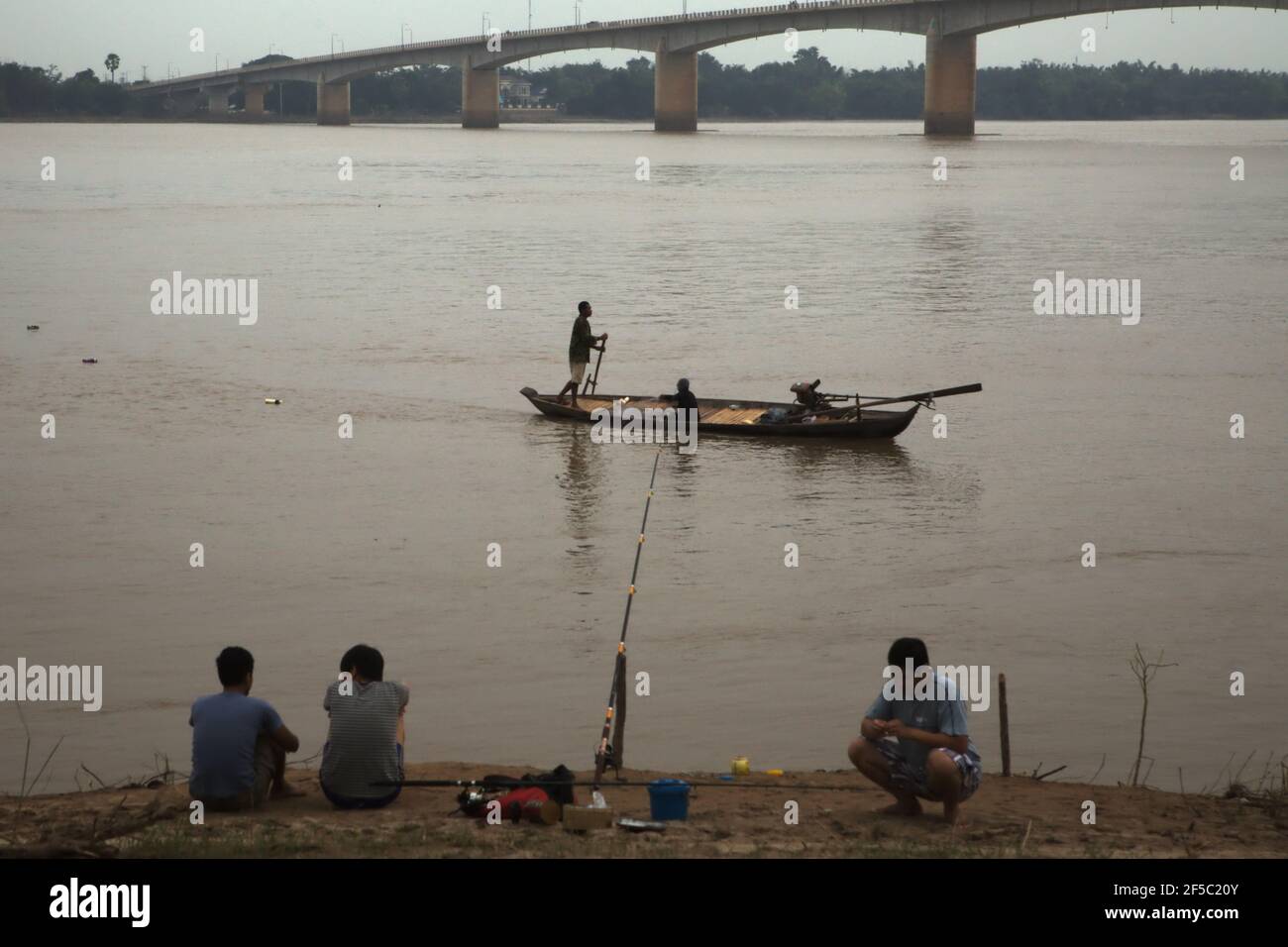 Pêcheurs sur la rive et sur un bateau en bois flottant sur le Mékong, à Kampong Cham, Cambodge. Fleuve transfrontalier qui traverse six pays, le Mékong vit des millions de personnes avec du poisson et de l'eau en Chine, au Myanmar, au Laos, en Thaïlande, au Cambodge et au Vietnam. Selon ONU eau dans leur Résumé de l'état d'avancement 2021 publié le 1er mars 2021 à Genève, seulement 22 pays ont signalé que tous les fleuves, lacs et aquifères qu'ils partagent avec les voisins sont couverts par des arrangements opérationnels de coopérations. Banque D'Images