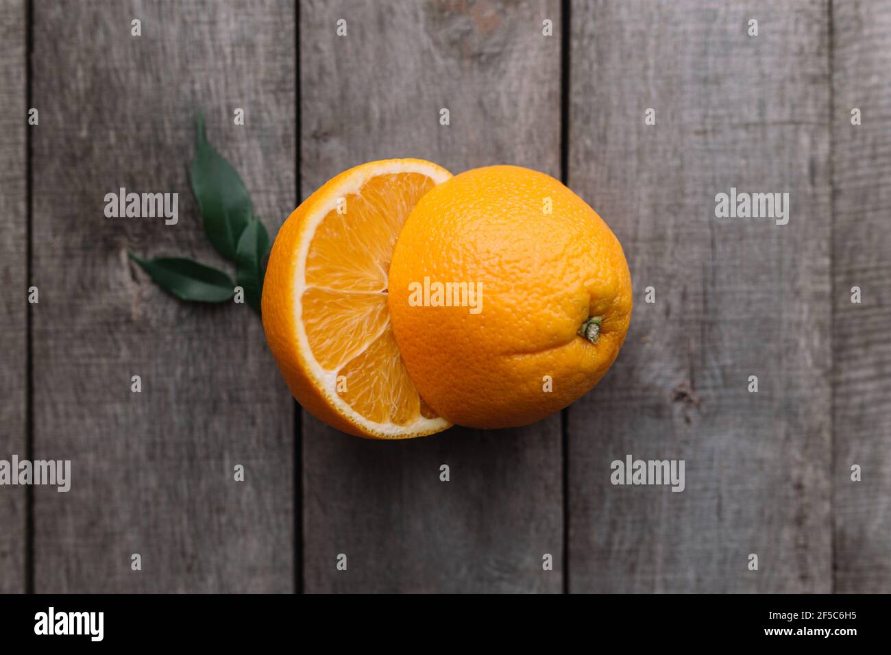 Moitiés de fruit orange sur fond en bois gris. Pulpe d'orange et feuilles vertes Banque D'Images