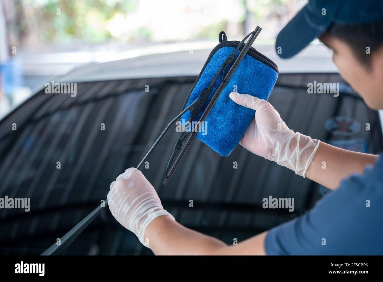 l'homme asiatique tient la microfibre à la main et essuie les essuie-glaces de pare-brise la voiture, le concept de service de lavage de voiture. Banque D'Images