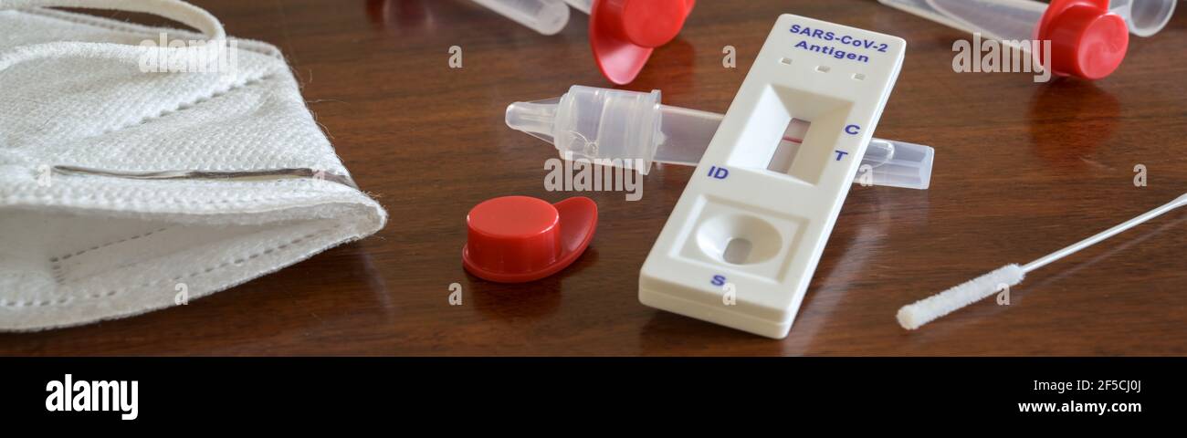 Kit d'auto-test d'antigène rapide pour Covid-19 avec résultat négatif, écouvillons nasaux, tubes, dispositif de détection et masque chirurgical ffp-2 sur un t en bois marron Banque D'Images