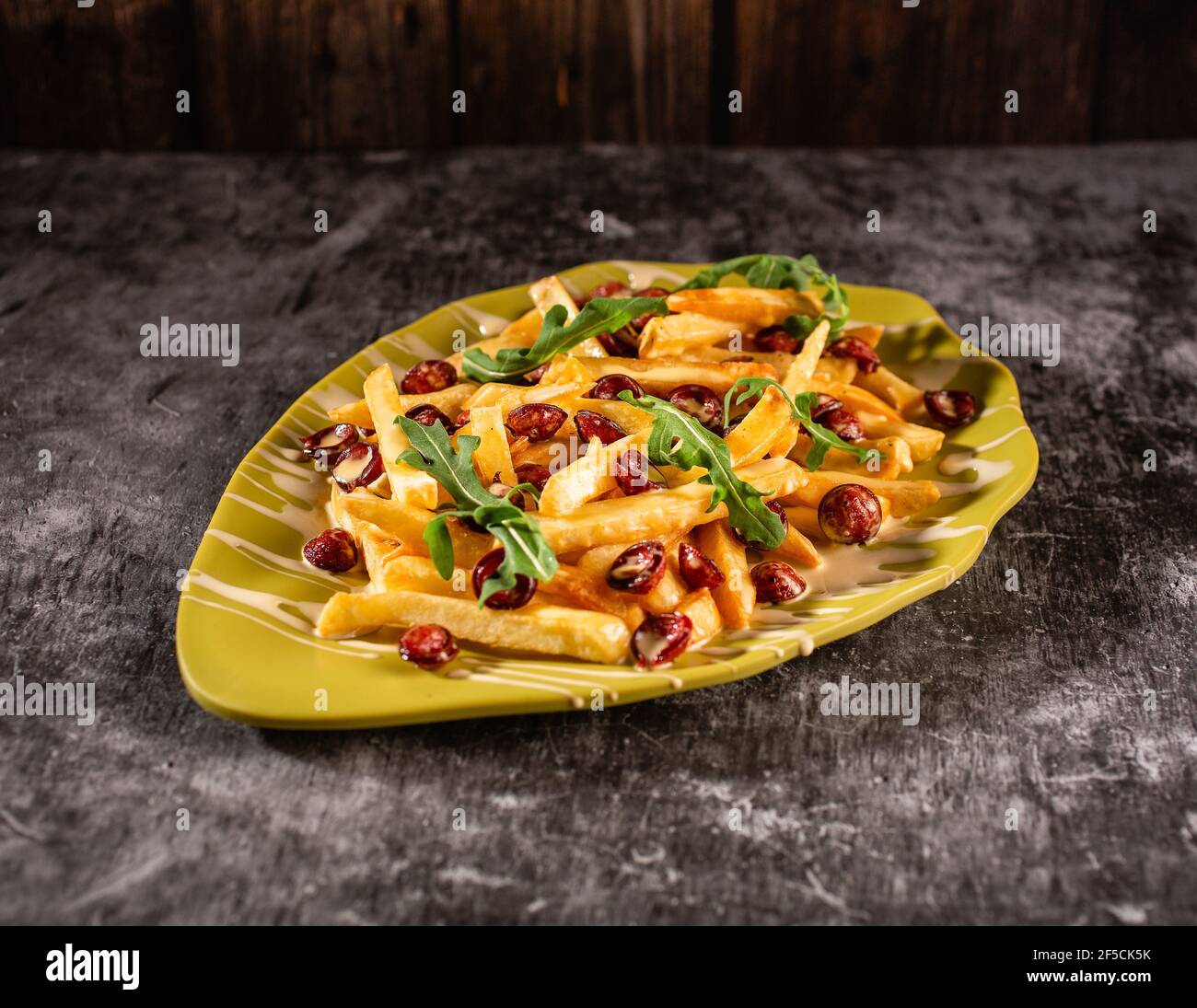 Déjeuner copieux composé de frites, saucisses et arugula. Plat dans une plaque jaune sur une table en béton gris. Le concept d'aliments nutritifs. Banque D'Images