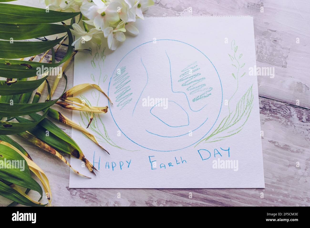 Texte de félicitations du jour de la terre et dessin de la planète avec décor floral sur fond blanc en bois Banque D'Images