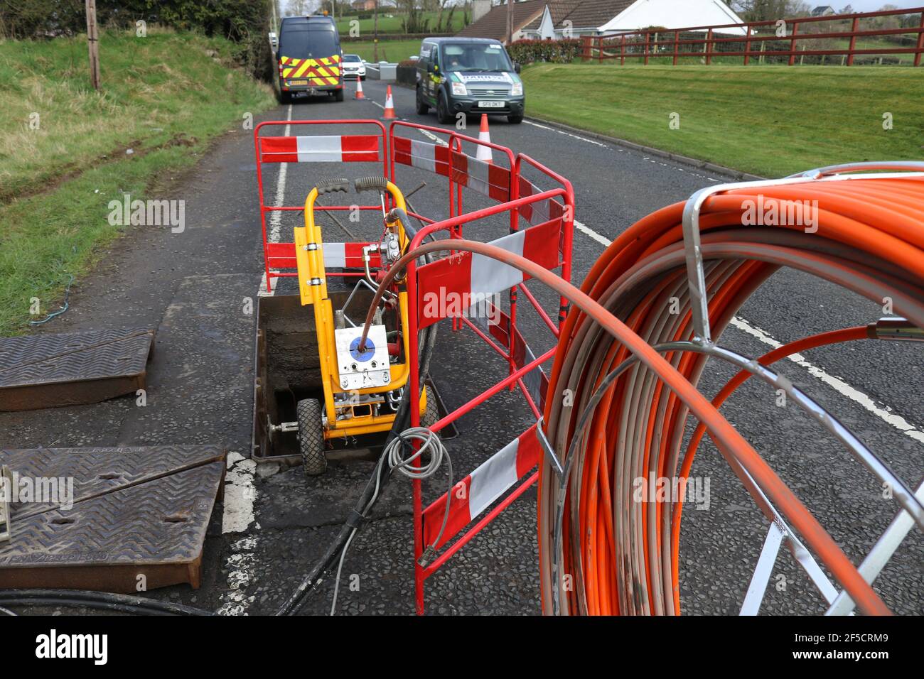 Une bobine de câble à fibre optique est introduite dans un trou d'homme lors de l'installation de câbles à fibre optique ruraux à l'extérieur de Lisburn, en Irlande du Nord, au Royaume-Uni Banque D'Images