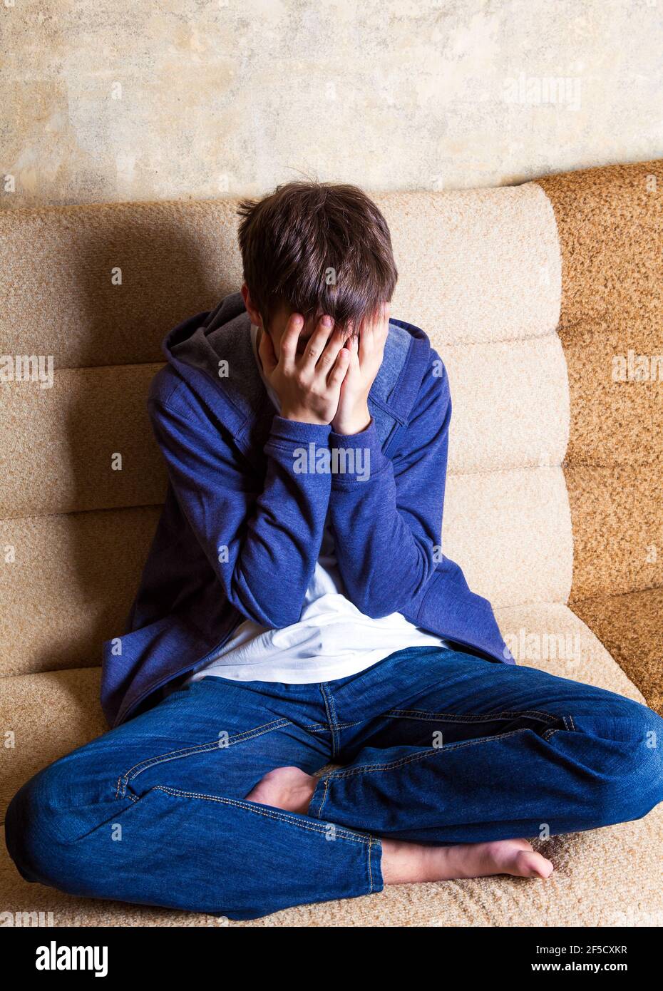 Triste adolescent assis sur le canapé dans la vieille maison Banque D'Images