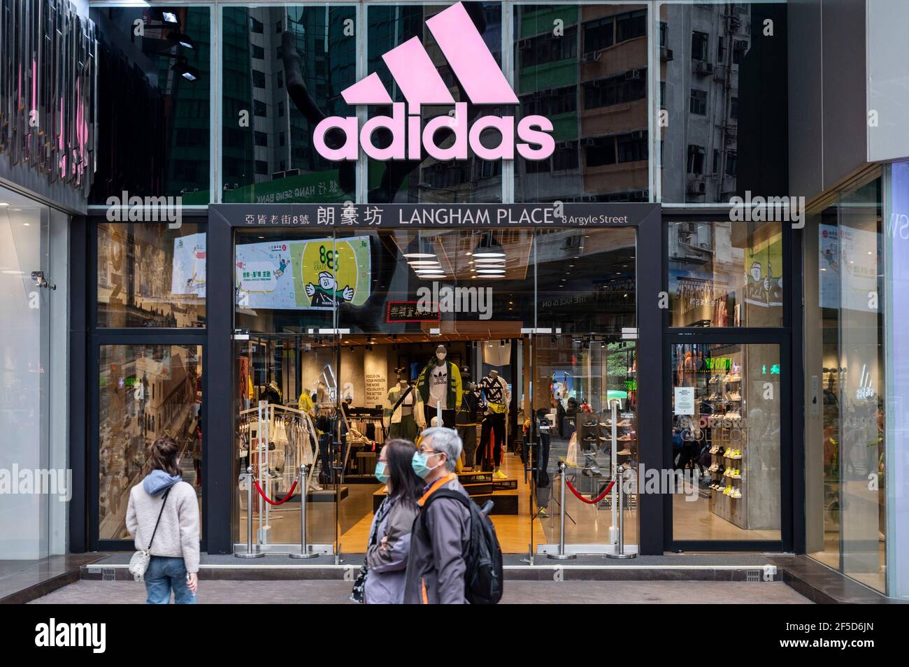 Hong Kong, Chine. 26 mars 2021. Des piétons marchent devant la marque allemande multinationale de vêtements de sport Adidas magasin et logo à Hong Kong. Crédit : SOPA Images Limited/Alamy Live News Banque D'Images