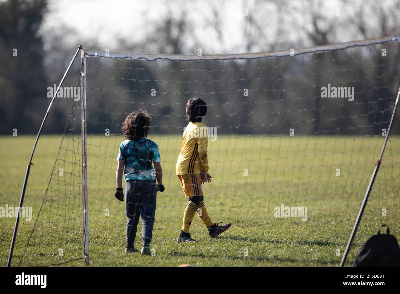 Oadby, Leicestershire. Angleterre. Mars 2021. Les garçons jouent au football dans un parc local. Banque D'Images