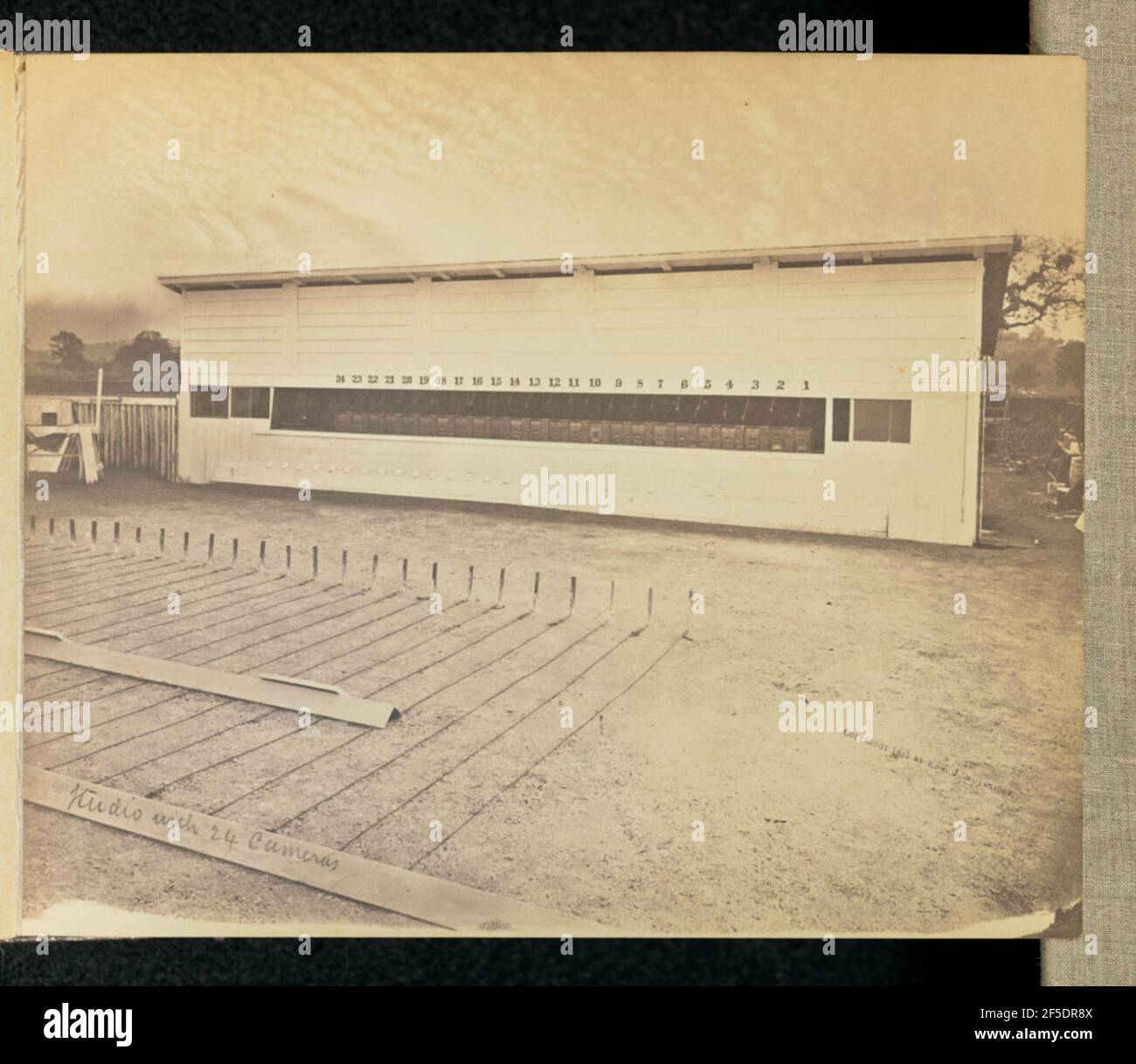 Studio avec 24 caméras. Vue d'un long hangar en bois avec une batterie de caméras face à une piste qui a été marquée à intervalles réguliers de distance. (Recto, print) en bas à gauche, au crayon, dans la main de l'artiste: 'Studio with 24 cameras'; (Verso, print) en haut à gauche, en crayon gras: 'Inscription partiellement rognée'; en haut à gauche, en crayon: '5'; Banque D'Images