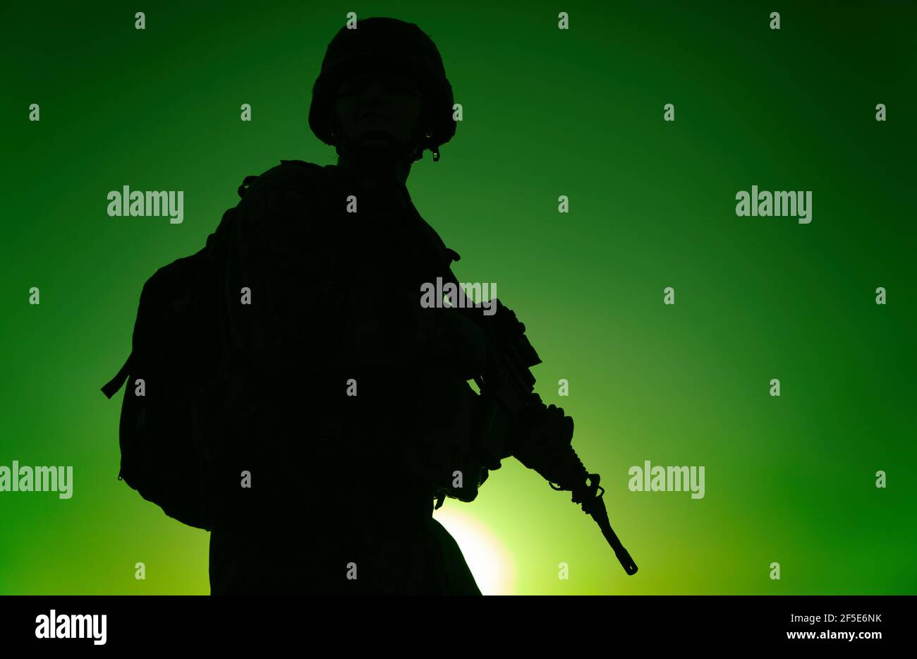 Silhouette de rifleman de l'armée dans un casque et des munitions, portant un sac à dos tactique, marchant avec une carabine de service sur fond de ciel de coucher de soleil. Contre-attaque des forces terroristes lors de la mission de nuit Banque D'Images