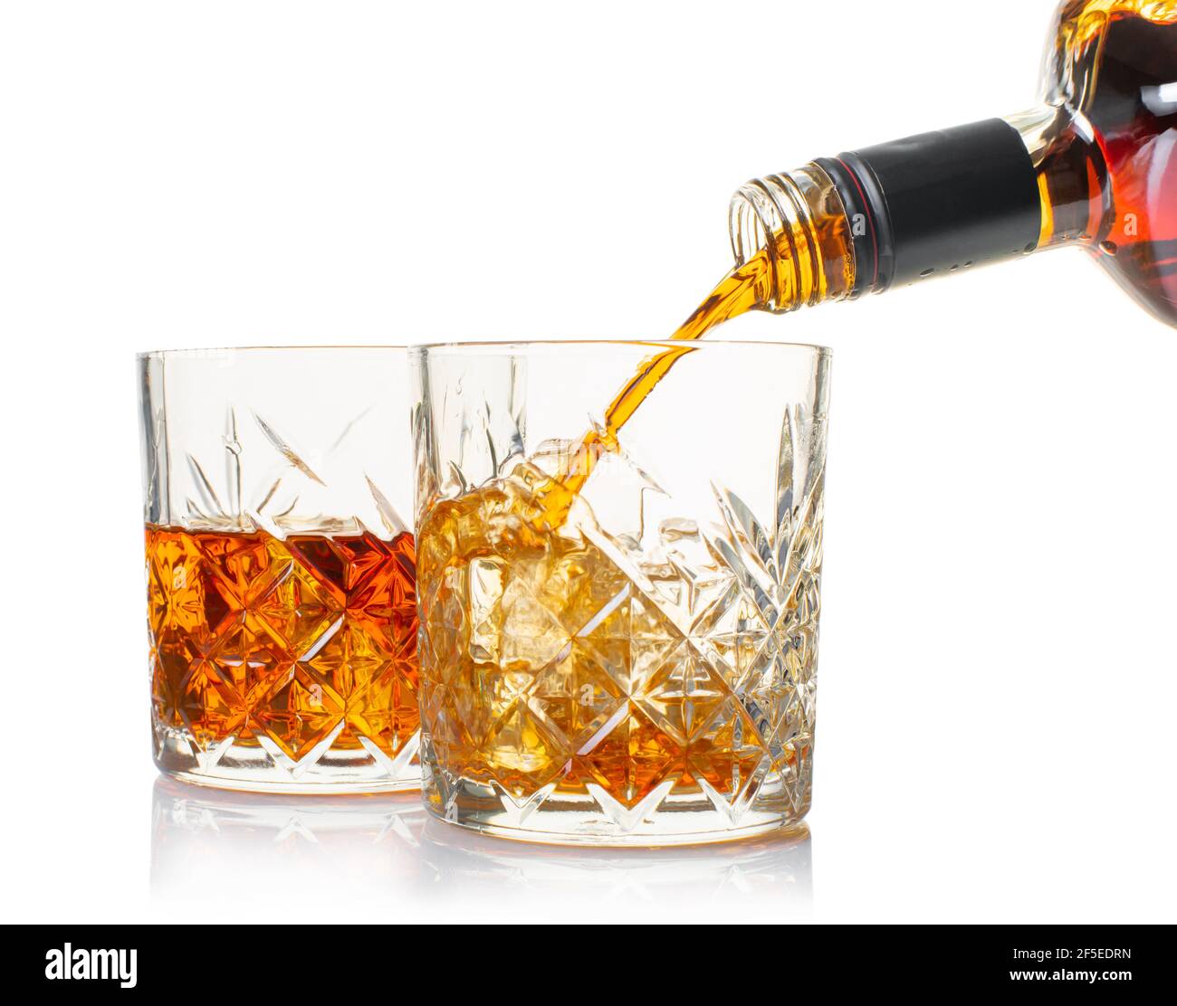 le whisky est versé dans un verre de la bouteille sur blanc arrière-plan isolé Banque D'Images