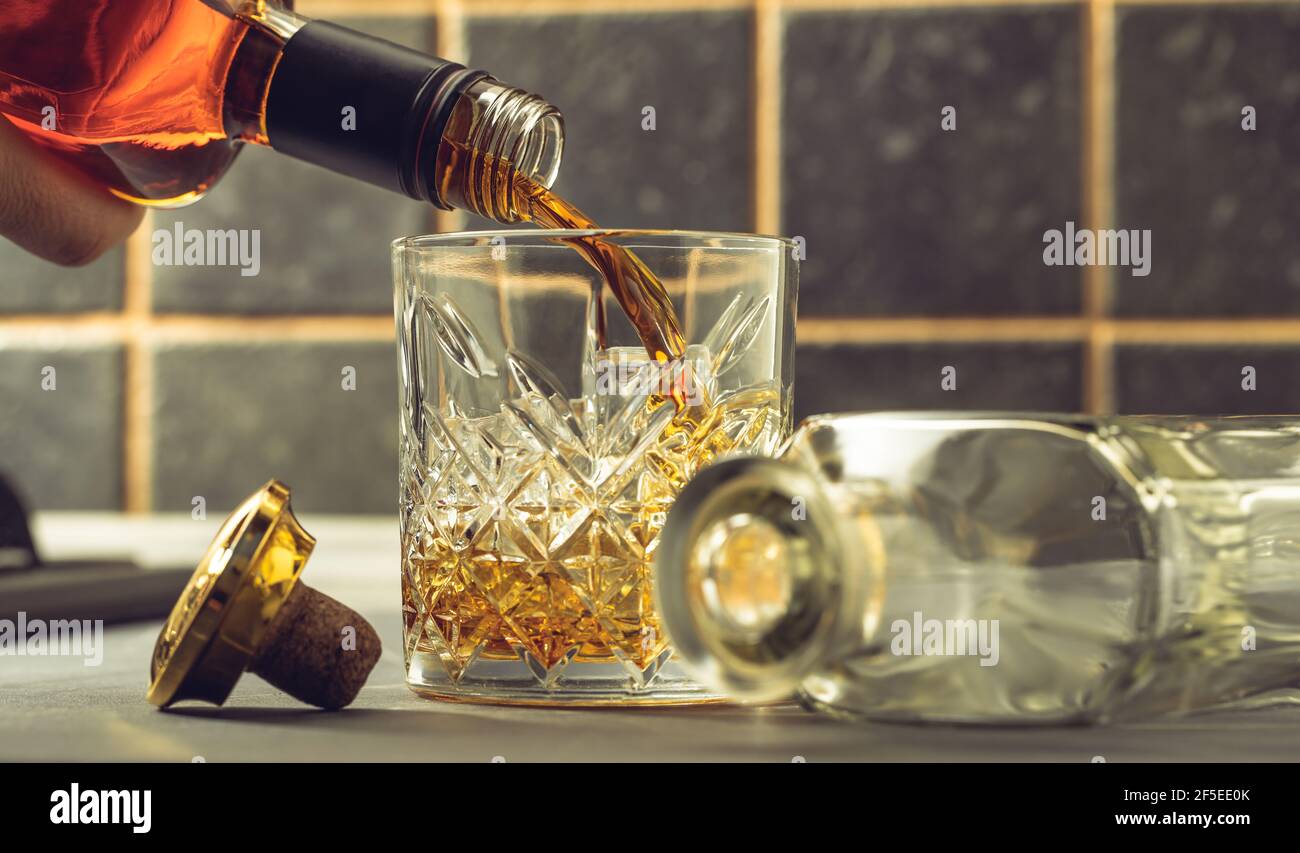 le whisky est versé dans un verre à partir d'une bouteille Banque D'Images