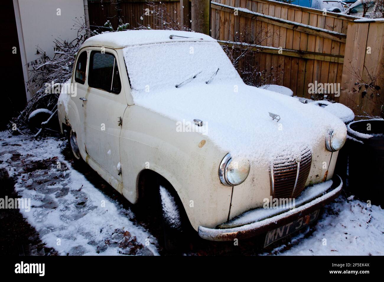 une petite vieille voiture couverte de neige dans une allée Banque D'Images