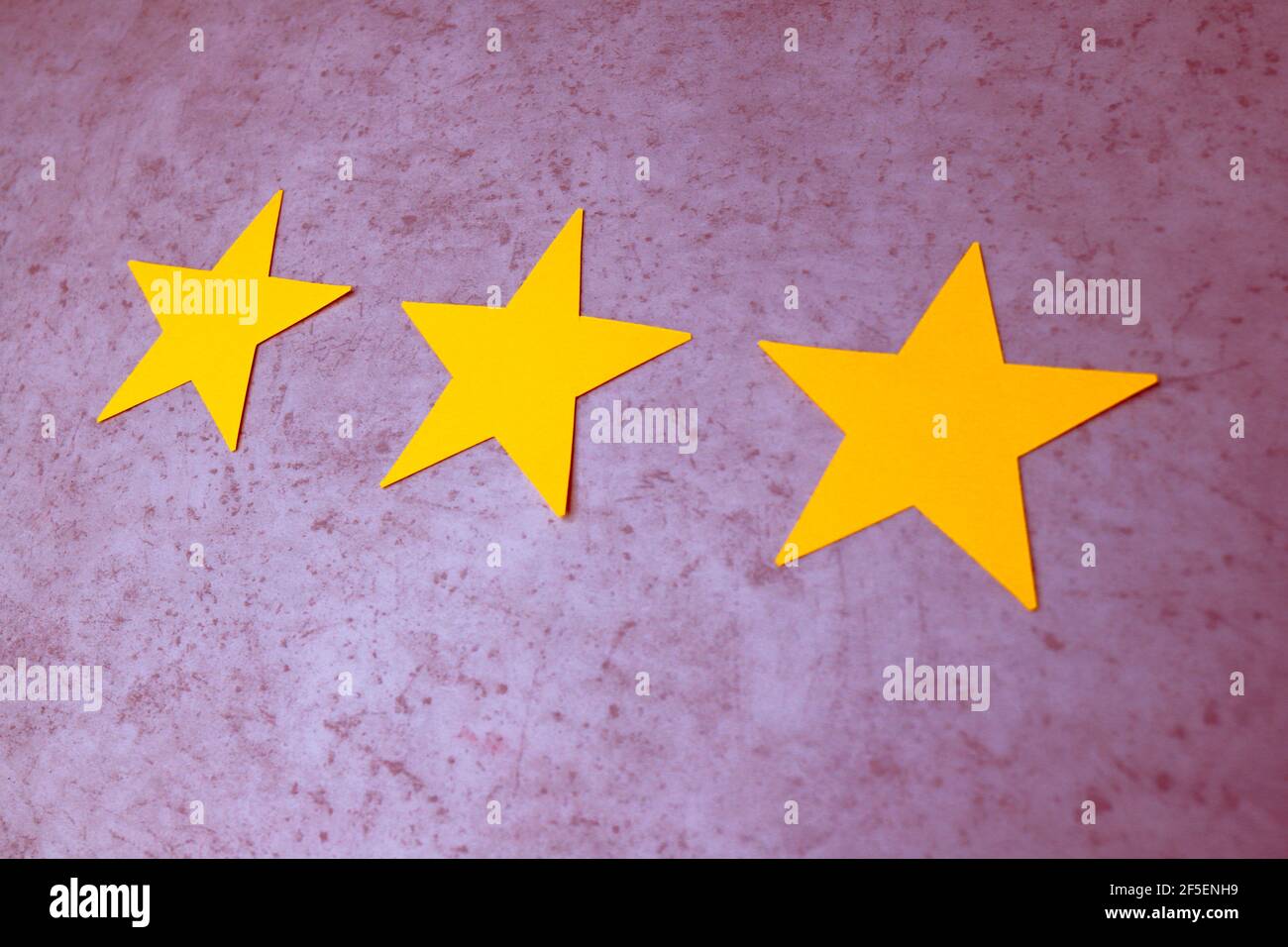 Concept d'expérience client. Trois étoiles jaunes sur fond de béton violet. Rétroaction négative Banque D'Images
