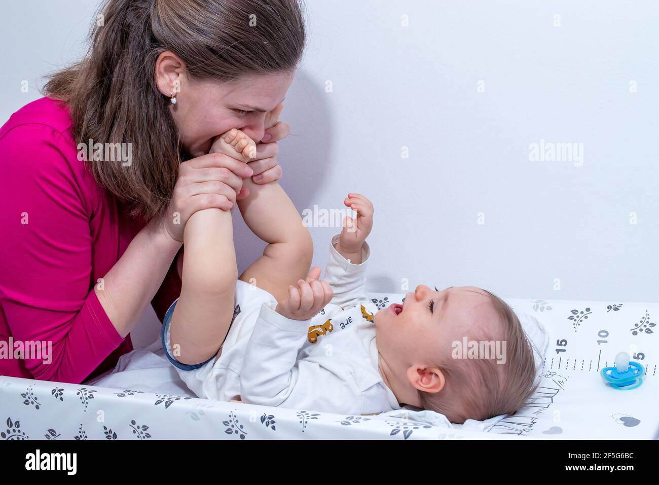 Mere Embrassant Les Petits Pieds De Bebe Apres Avoir Change Une Couche Pour Son Petit Garcon Souriant Photo Stock Alamy