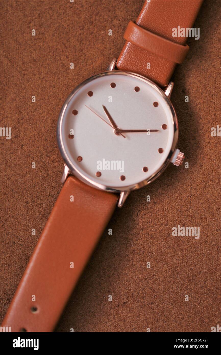 Montre avec bracelet en cuir marron sur fond de cuir marron. Accessoires en cuir véritable. Notion : horloge et heure.vue de dessus, copier l'espace.regarder avec un Banque D'Images