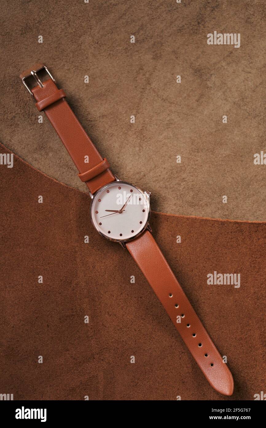 Montre avec une sangle en cuir marron sur un fond en cuir marron véritable. Accessoires en cuir véritable. Horloge et heure. Faites attention avec une sangle en cuir Banque D'Images
