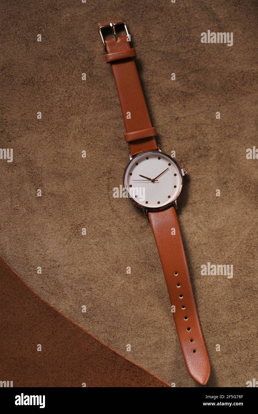 Montre avec une sangle en cuir marron sur un fond en cuir marron véritable. Accessoires en cuir véritable. Notion : horloge et heure.vue de dessus.regarder avec un Banque D'Images