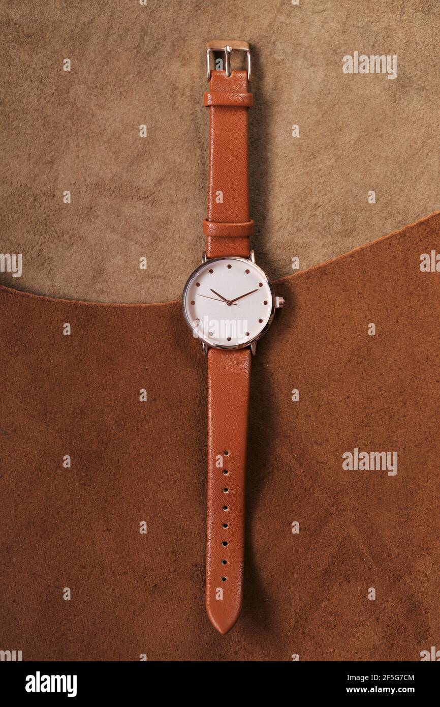 Montre avec une sangle en cuir marron sur un fond en cuir marron véritable. Accessoires en cuir véritable. Horloge et heure.vue de dessus, copier l'espace.regarder avec un Banque D'Images