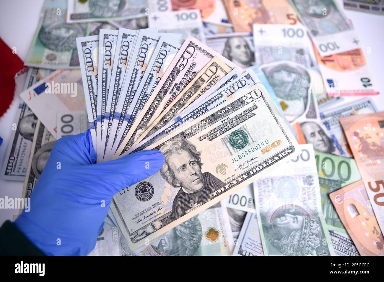 WROCLAW, POLOGNE - 4 FÉVRIER 2021 : main photo avec gant contenant des billets de banque en dollars. Banque D'Images
