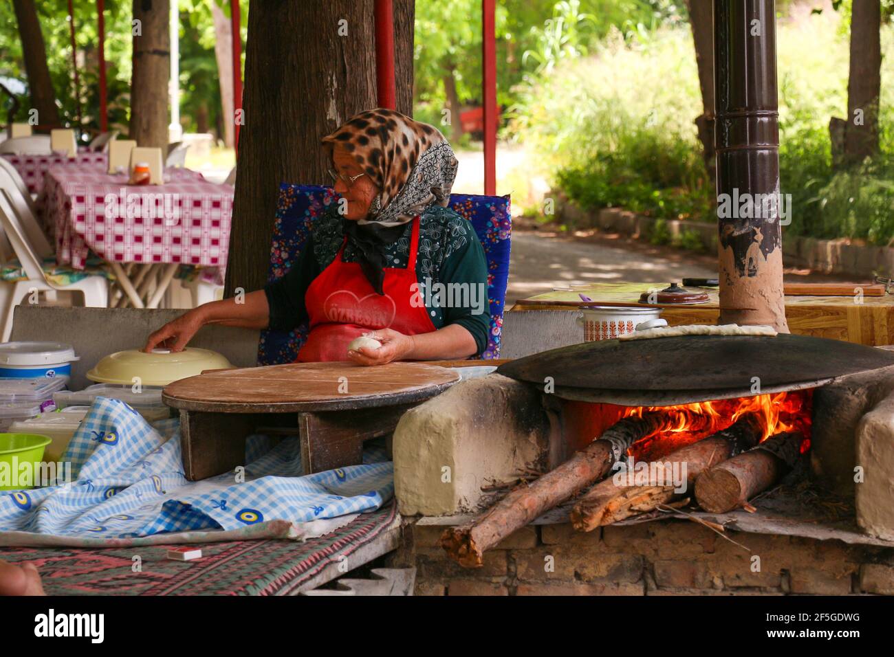 ANTALYA, TURQUIE - 30 mai 2015 : traditionnellement habillée, la vieille femme est makingTurkish crêpes au feu dans le parc. Banque D'Images