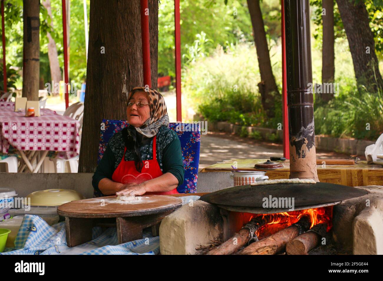 ANTALYA, TURQUIE - 30 mai 2015 : traditionnellement habillée, la vieille femme est makingTurkish crêpes au feu dans le parc. Banque D'Images